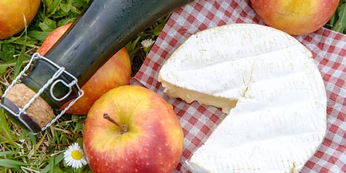 several apples with cider and camembert in the grass